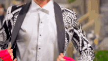 a man in a black and white jacket is holding a pink ribbon