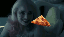 harley quinn is holding a slice of pepperoni pizza in her hand
