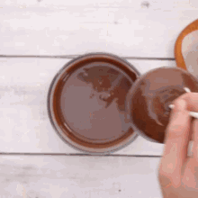 a person is pouring chocolate sauce into a glass with a spoon