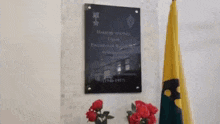 a plaque on a wall next to a vase of roses