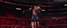 a wrestling match is taking place in front of a crowd and a wrestler is laying on his back .