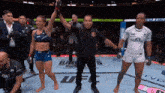 a referee holds up a female fighter 's hand in a ufc ring
