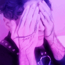 a person covering their face with their hands with a tattoo on their hand that says ' i 'm sorry '