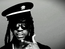 a man with dreadlocks wearing a hat and sunglasses