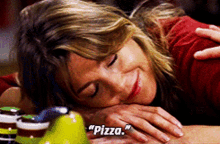 a woman is smiling while laying on a table with the words pizza written on the bottom
