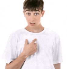 a young boy in a white t-shirt is pointing at his chest .