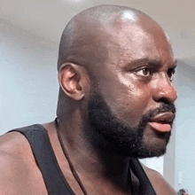 a bald man with a beard is wearing a tank top