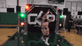 a wrestler is jumping in front of a sign that says cap on it