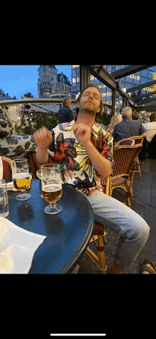 a man is sitting at a table with two glasses of beer