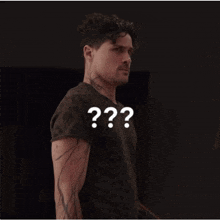 a man with a tattoo on his arm is standing in front of a sign that says " question "