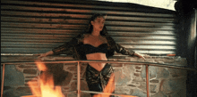 a woman in a black crop top is leaning on a railing