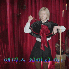 a woman in a cape stands in front of a red curtain with korean writing on it