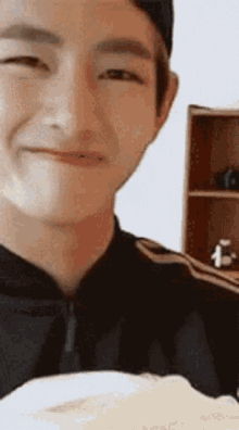 a young man is smiling while holding a plate of food in front of his face .