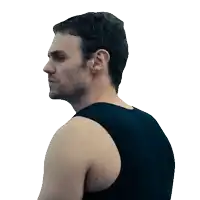 a man in a black tank top looks to his left