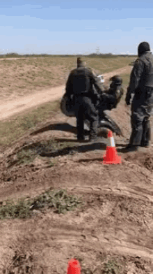 a man riding a motorcycle on a dirt road next to a red and white cone