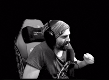 a man wearing headphones and a beanie is giving the middle finger in front of a microphone