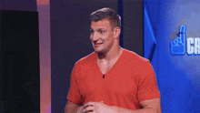 a man in a red shirt is smiling in front of a sign that says ' cb '