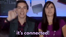 a man and a woman are sitting in front of a sign that says it 's connected ..