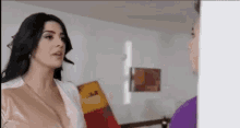 a woman is standing next to a man in a living room and talking to him .