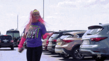 a woman with pink hair wearing a purple shirt that says ' wwe ' on it