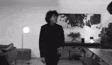 a man in a suit is standing in a living room holding a drink .
