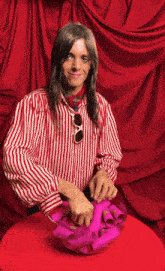 a man wearing a red and white striped shirt is holding a bowl of pink hair rollers