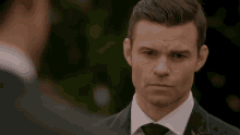 a man in a suit and tie looks at the camera
