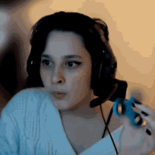 a woman is wearing headphones and holding a blue toy