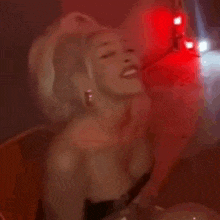 a woman is kissing another woman in a dark room with red lights behind her .