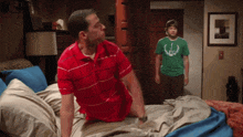 a man in a red shirt is laying on a bed
