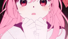 a close up of a girl with pink hair and red eyes holding her hands together .
