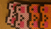 a row of pink and orange perler beads with the letters e and b on them