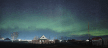 the aurora borealis shines brightly in the night sky over a fenced in area