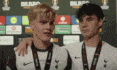 two young men wearing medals are standing next to each other