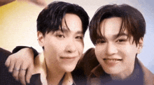 a couple of young men are standing next to each other and smiling .