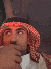 a man wearing a head scarf is covering his mouth