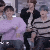 a group of young men are sitting on a bench and dancing together .