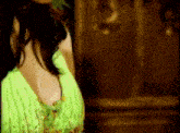 a woman in a green dress is standing in front of a mirror