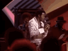 a man is singing into a microphone while standing on a stage .