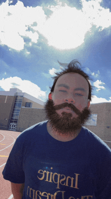 a man with a beard and mustache wears a blue shirt that says ' stiga ' on it