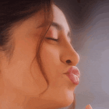 a close up of a woman blowing a kiss with her eyes closed .