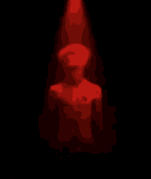 a statue of a man is standing in a dark room under a red light .