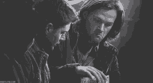 a black and white photo of two men with the website mostlyvid.com in the bottom right corner