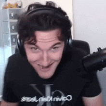 a man wearing headphones is sitting in front of a microphone .