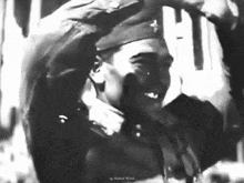 a black and white photo of a man in a military uniform waving his hands in the air .