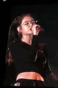a woman is singing into a microphone on stage .