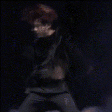 a man with red hair is dancing on a stage in the dark .