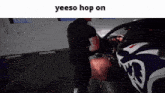 a man standing next to a car with the words yeeso hop on on the bottom