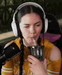 a woman wearing headphones is drinking a drink through a straw .
