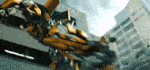 a yellow transformer is flying through the air in front of a building .